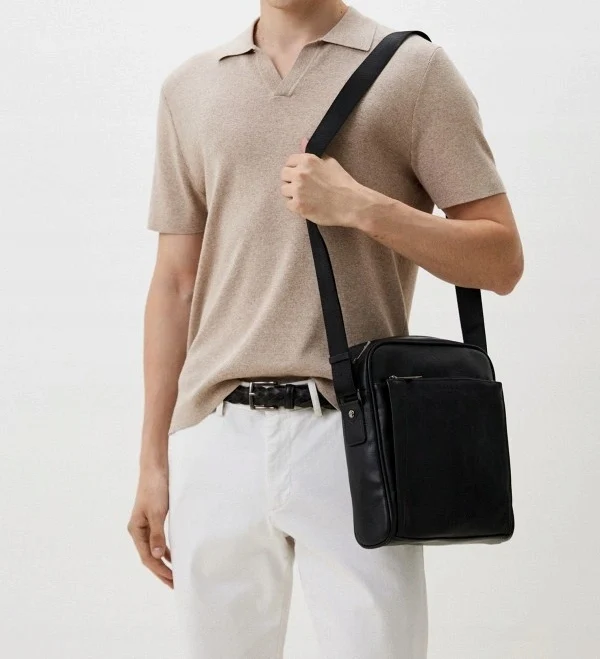 A man posing with a stylish cross-body bag